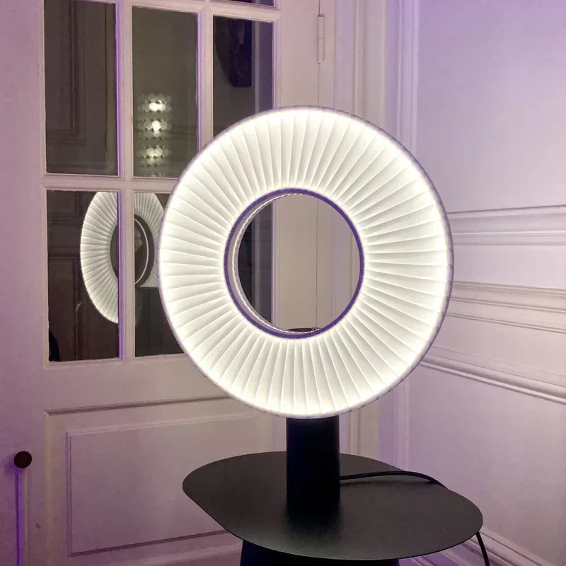 Lampe de table à anneau lumineux plissé et pied cylindrique noir