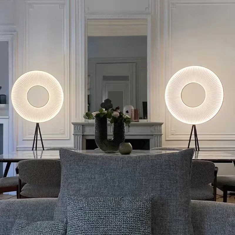 Deux lampadaires à anneau lumineux plissé disposés derrière un canapé gris