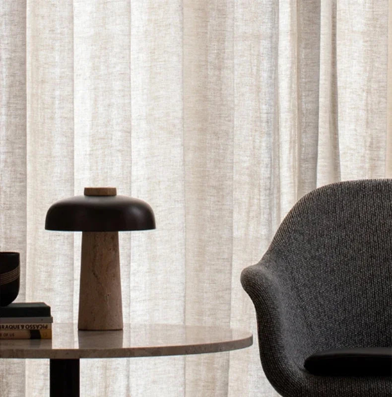 Lampe nordique éteinte avec abat-jour noir près d’un fauteuil gris