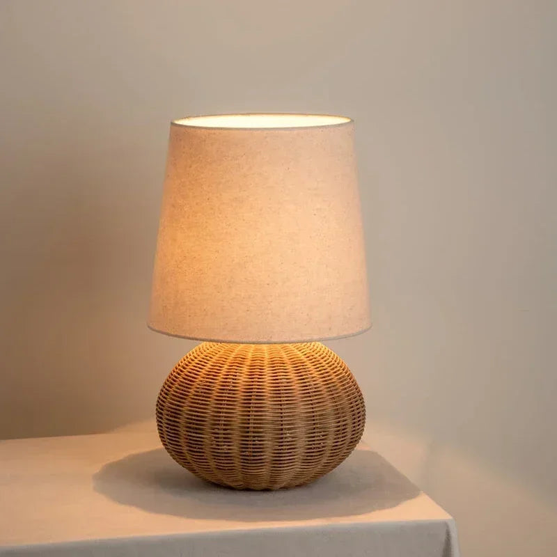 Lampe Wabi-Sabi allumée avec pied arrondi tressé et abat-jour clair