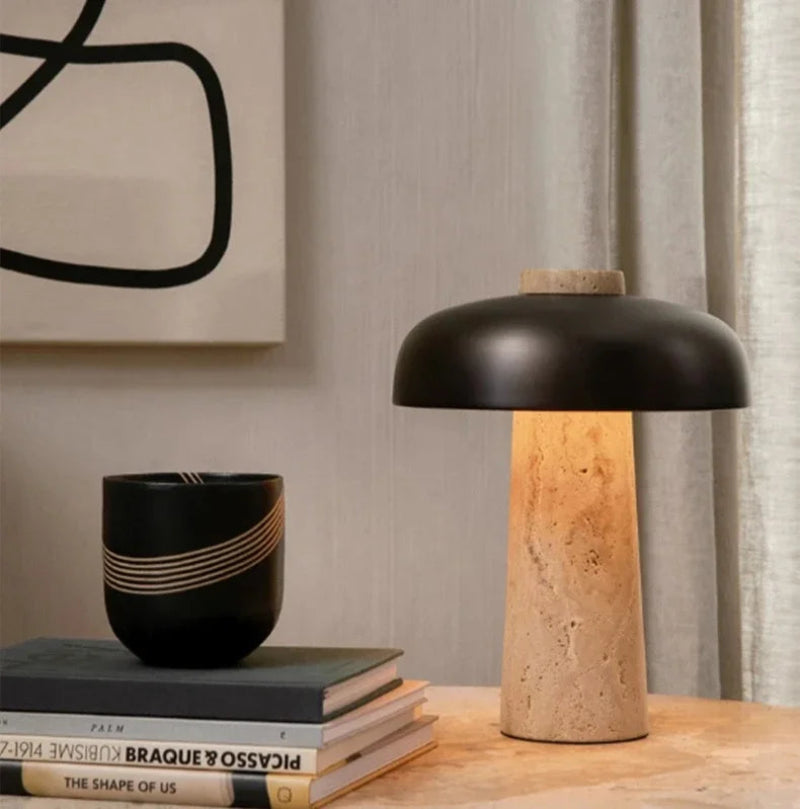 Lampe nordique allumée sur une table avec livres et vase noir