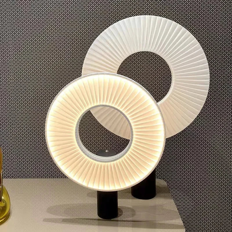 Deux lampes rondes à abat-jour annulaire plissé et pied noir, allumée et éteinte