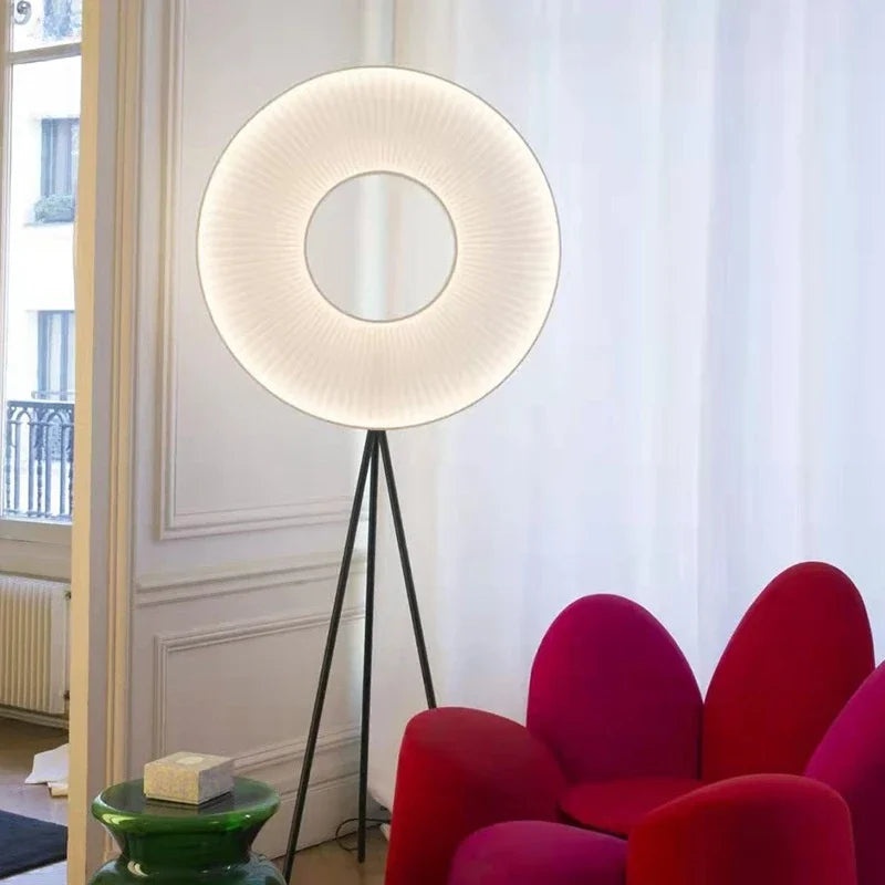 Lampadaire à abat-jour rond plissé sur trépied noir près d’un fauteuil rouge